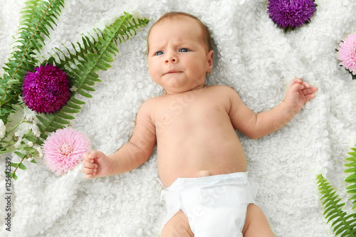Cute baby lying on bedsprea...