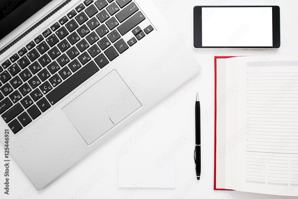 White desk with laptop, smartphone and notebook. Blank mobile phone screen and notepad page with computer keyboard, flat lay. Free space for text White desk with laptop, smartphone and notebook. Blank mobile phone screen and notepad page with computer keyboard, flat lay. Free space for text