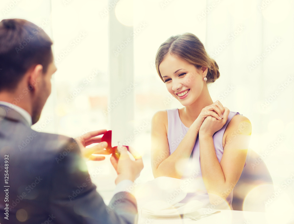 excited young woman looking at boyfriend with ring