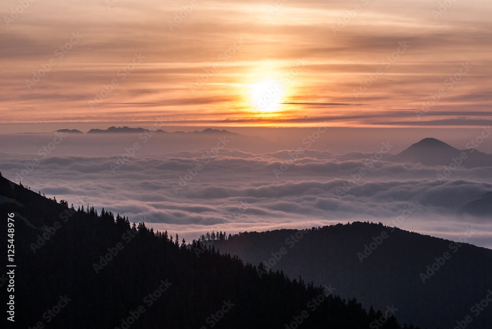 autumn morning panorama from Chata pod Chlebom in Mala Fatra mountains with only Tatras mountain range and Velky Choc hill above misty level with sun 