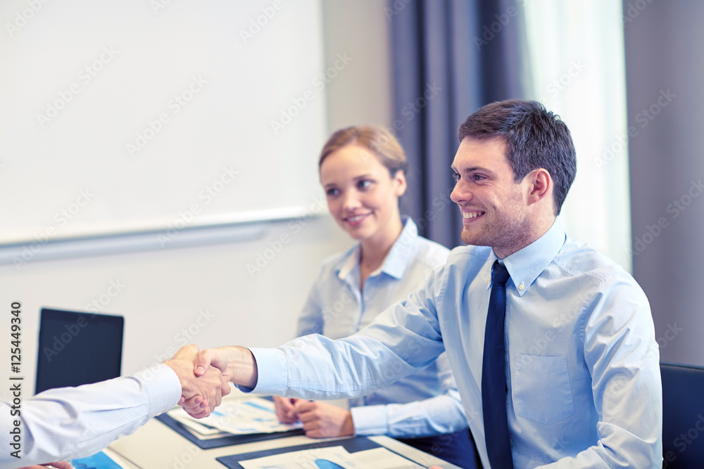 smiling business team shaking hands in office smiling business team shaking hands in office