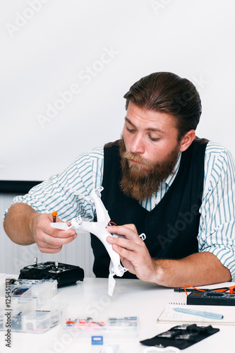 Repairman disassembling broken drone in office. Electrician screwing quadrocopter propeller for repair. Electronics, innovation, hobby, technology concept