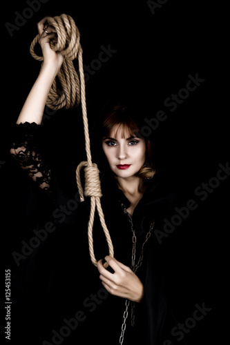 mysterious young woman holding loop of the rope. on a dark background
