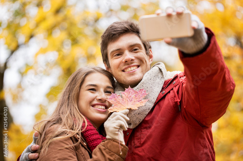 couple taking selfie by smartphone in autumn park
