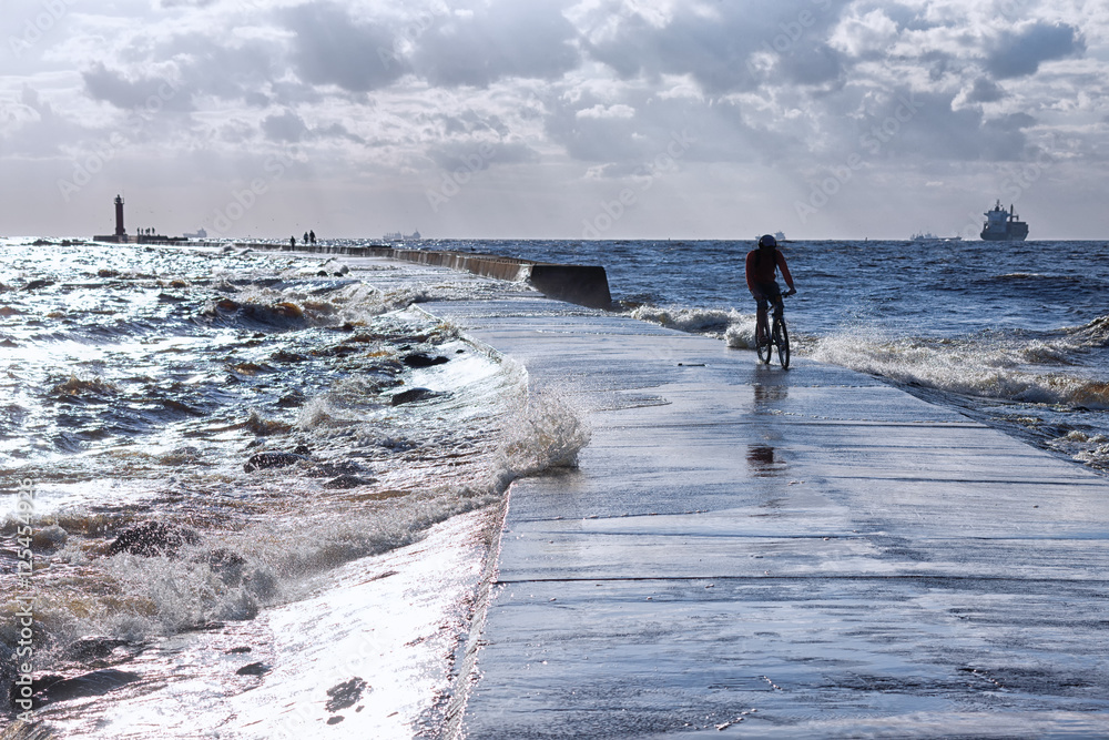 Cyclist on a dam in the sea in a storm