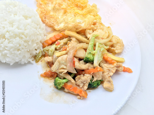 stir fry vegetables with chicken fillet, fried egg with rice in white dish on white background.