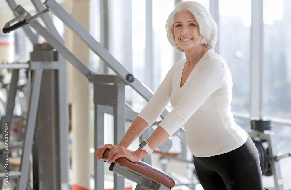 Cheerful fit senior woman using gym equipment. Cheerful fit senior woman using gym equipment.