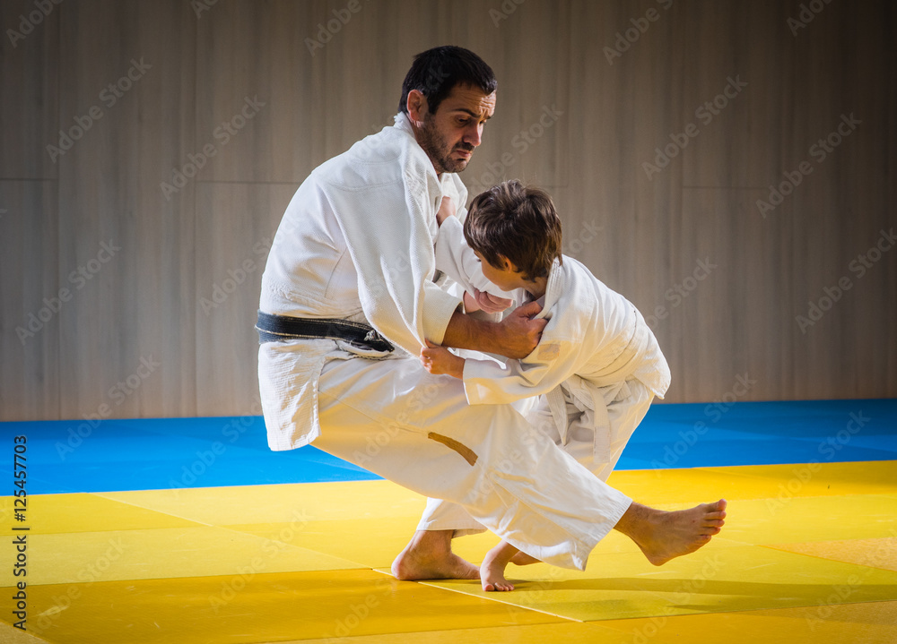 Man and young boy are training judo throw