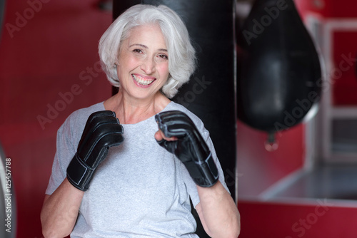 Smiling senior woman holding hands like a boxer. © zinkevych