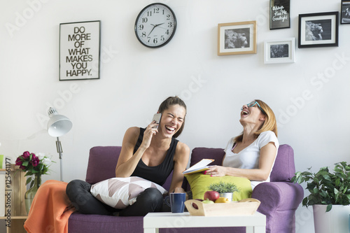 Happy young female friends conversing in the living room at home