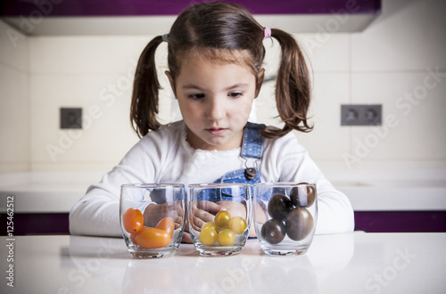 Quadro em tela Little girl observing cherry tomatoes varieties colors