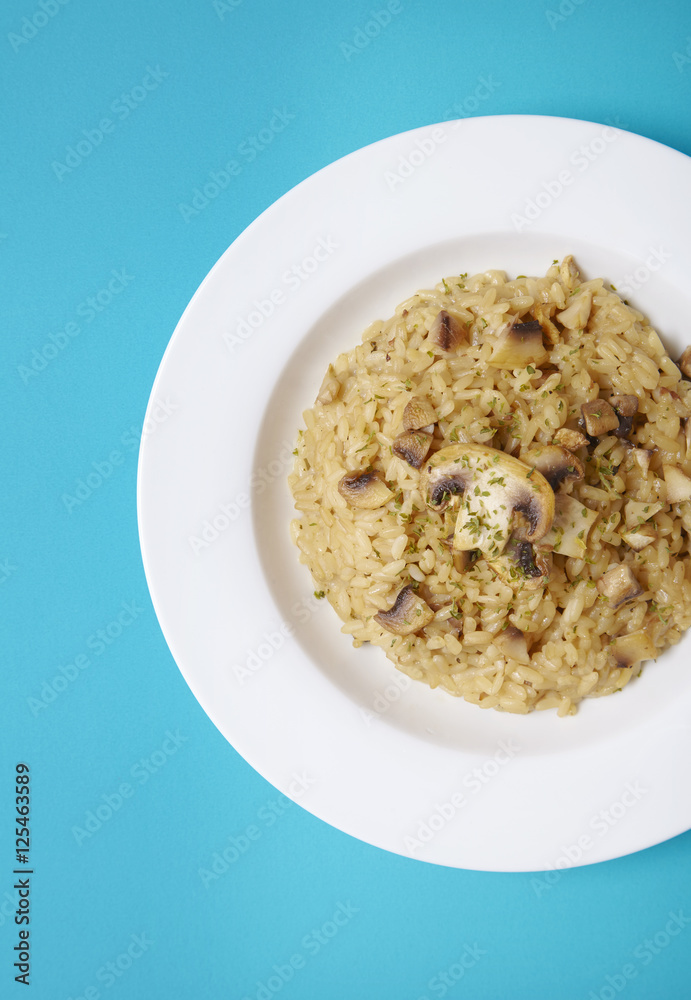 A dish of chicken and mushroom risotto on a bright blue background A dish of chicken and mushroom risotto on a bright blue background