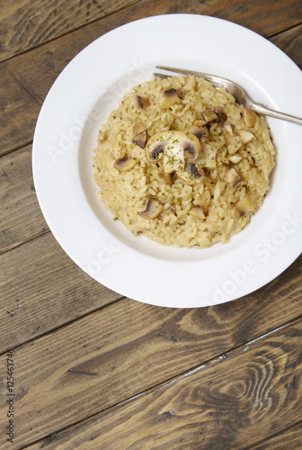 A dish of mushroom risotto on a rustic wooden table top background