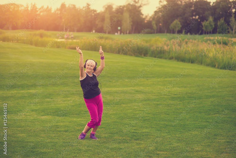 Woman in headphones dancing. Senior lady on grass background. Open your mind to music. World famous hits. Woman in headphones dancing. Senior lady on grass background. Open your mind to music. World famous hits.