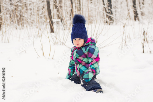 Toddler child playing in a snow in winter.