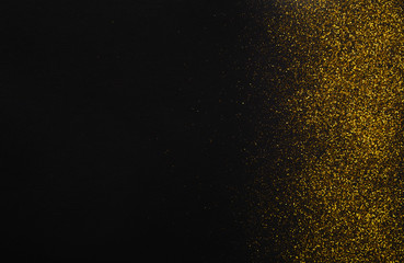 Golden glitter sand texture border on black, abstract background.