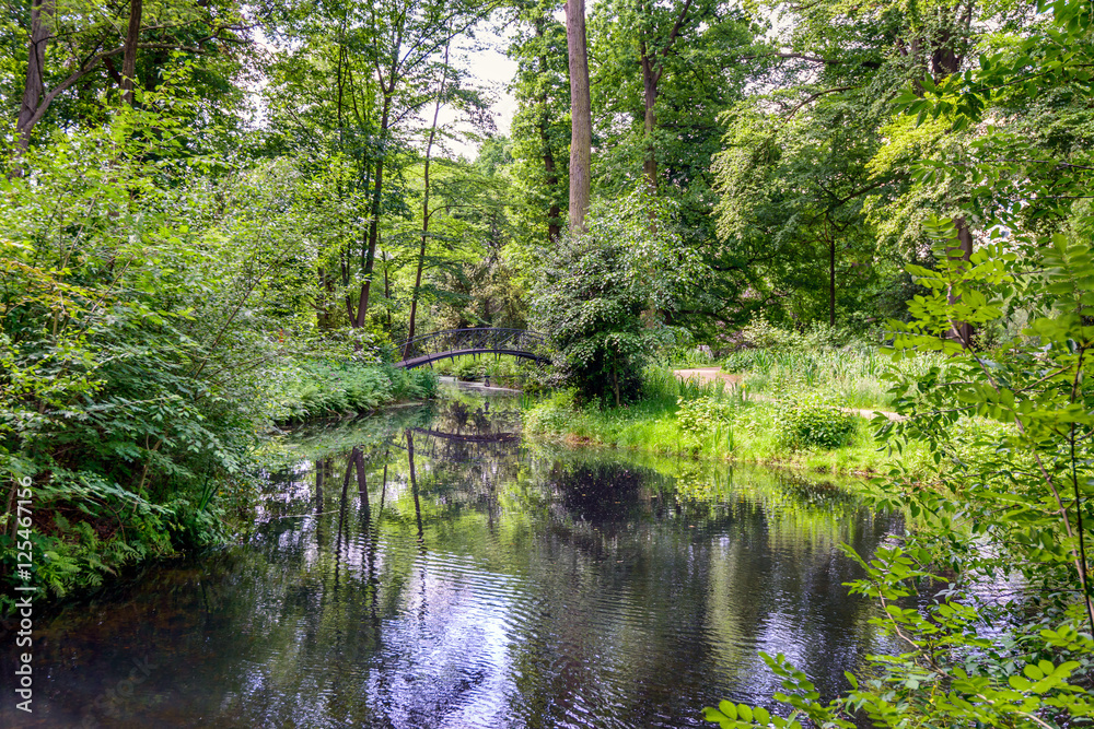 Idyllic park with a canal and an old arch bridge