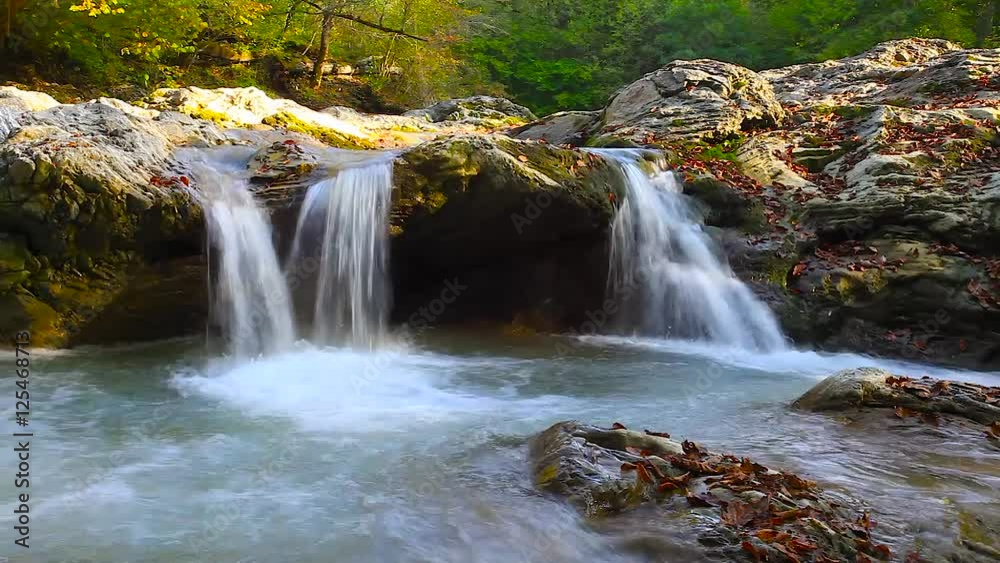 A river flows over rocks in this beautiful scene in the mountains in autumn A river flows over rocks in this beautiful scene in the mountains in autumn