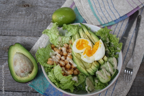 healthy salad in a bowl. avocado, chickpeas, cucumber and egg. more greens every day