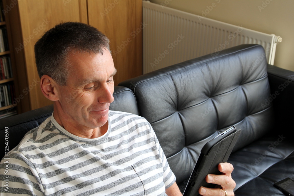 Happy older man finding something amusing on his tablet computer Happy older man finding something amusing on his tablet computer