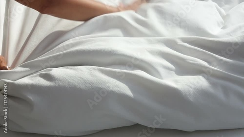 closeup of woman throwing white blanket on bed
