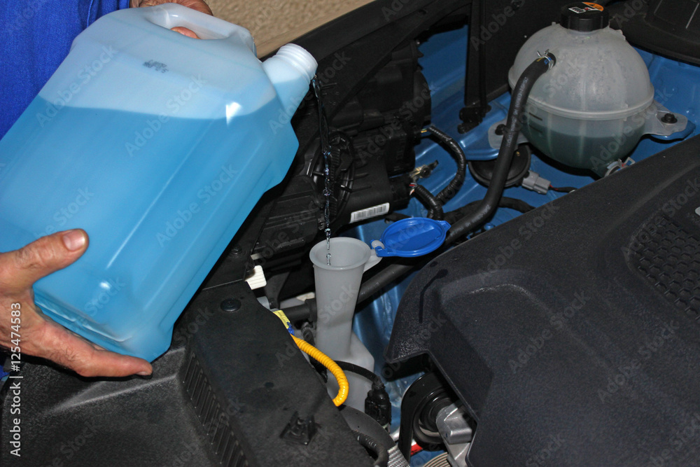 Mecánico llenando el depósito del líquido limpiaparabrisas del coche Stock  Photo
