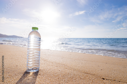 Vacation concept. Plastic bottle of drinking water on the sand of the sea beach.