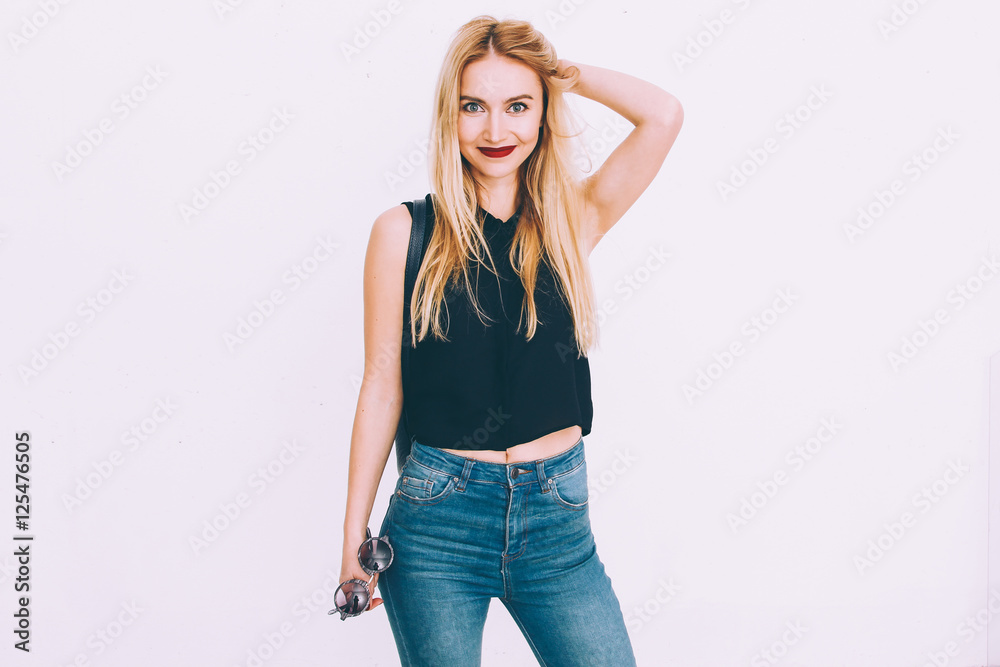 beautiful young blond girl standing against white wall,wearing jeans ...