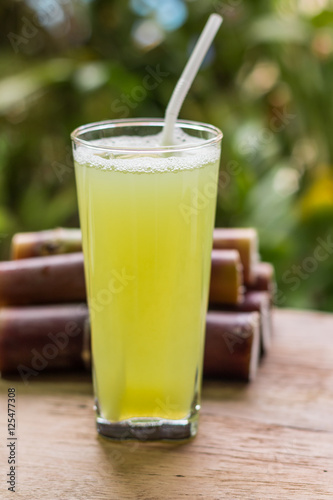 Sugarcane juice with piece of sugarcane on wooden background