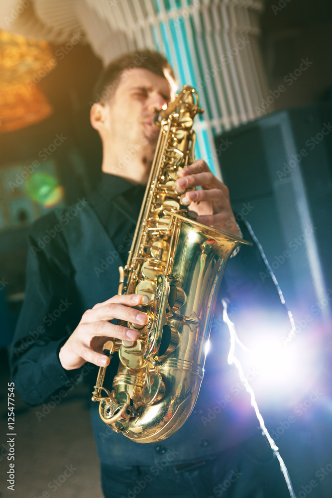 Obraz premium A young man in a suit playing on saxophone musical instrument