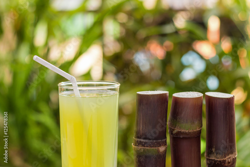 Sugarcane juice with piece of sugarcane on wooden background
