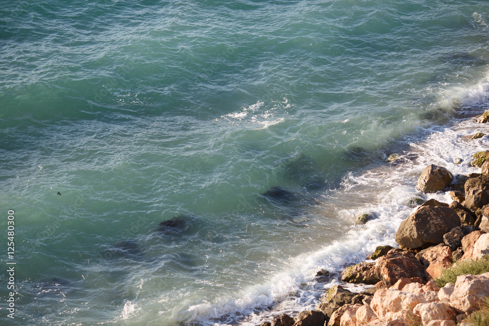 Fototapeta premium Waves lapping on large coastal rocks