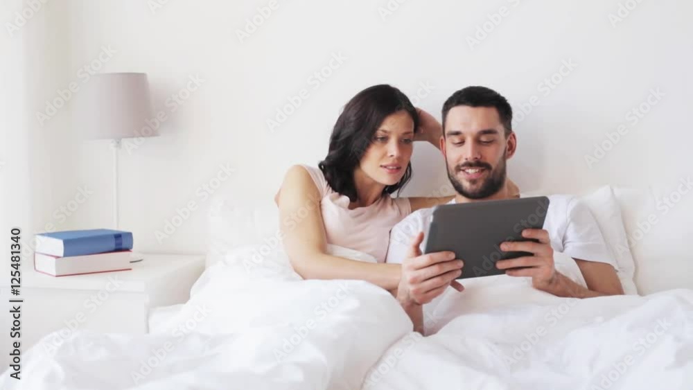 smiling couple in bed with tablet pc computer smiling couple in bed with tablet pc computer
