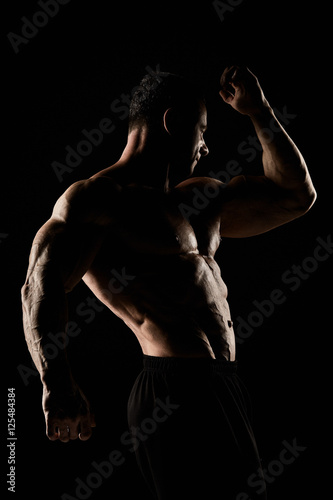 torso of attractive male body builder on black background.