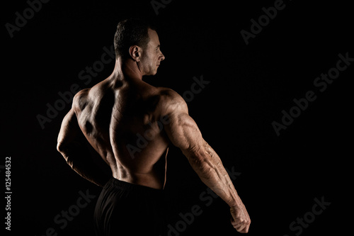 torso of attractive male body builder on black background. © master1305
