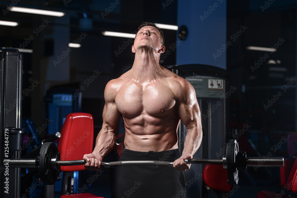 Handsome athletic fitness man posing and trains in the gym. Handsome athletic fitness man posing and trains in the gym.