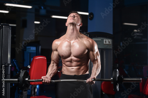 Handsome athletic fitness man posing and trains in the gym.