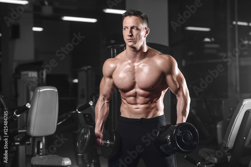 Handsome athletic fitness man posing and trains in the gym.