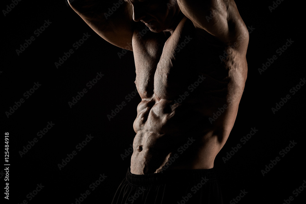 torso of attractive male body builder on black background.