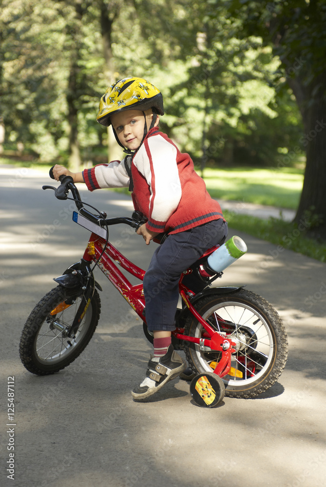 Young boy riding his first bicycle with training wheels 