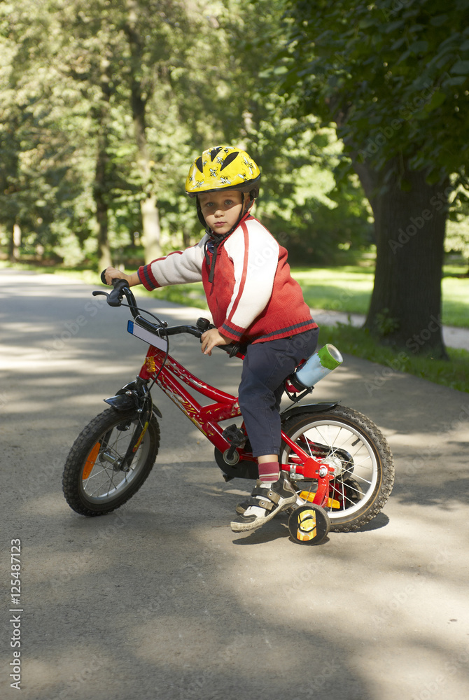 Fototapeta premium Young boy riding his first bicycle with training wheels 
