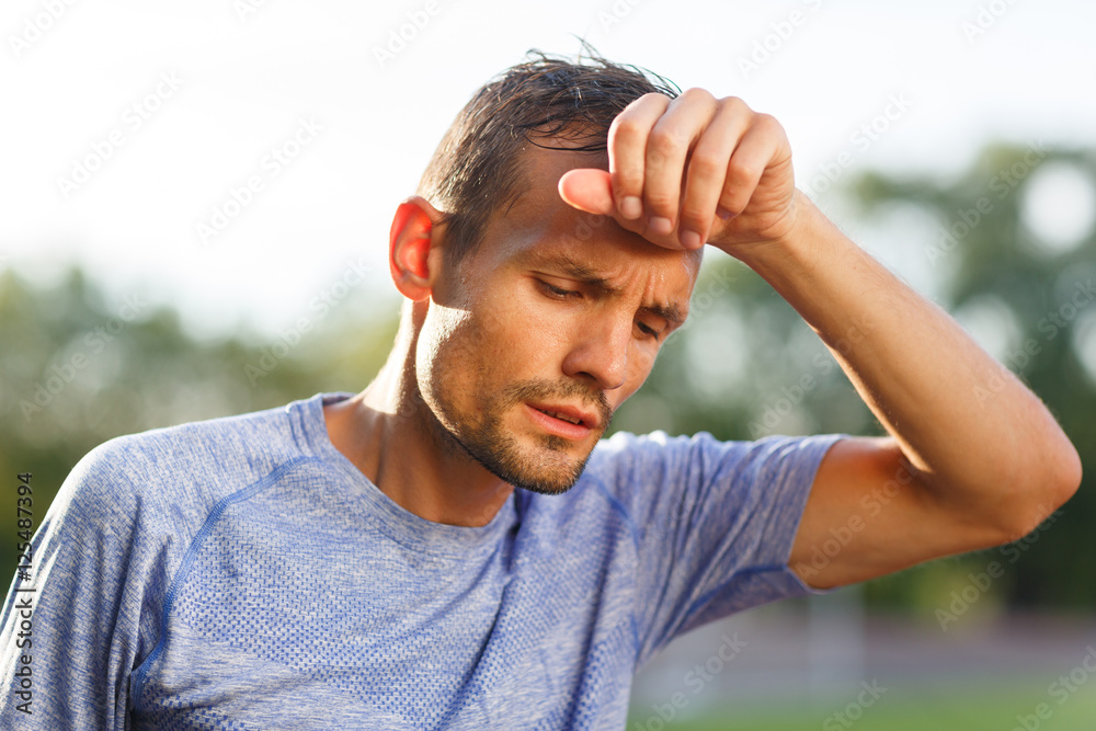 Tired athlete wiping with hand sweat from forehead closeup Tired athlete wiping with hand sweat from forehead closeup