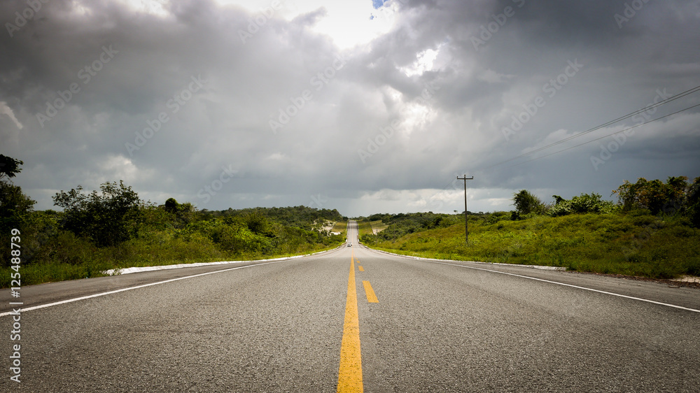 Empty rural road, Maranhao, Brazil. A long and empty straight road in rural northern Brazil with ominous storm clouds over the horizon.