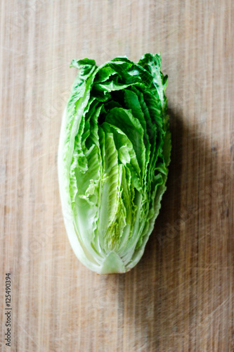 Fresh Romaine lettuce hearts on a bamboo cutting board with a dark background