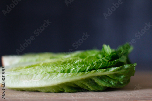 Fresh Romaine lettuce hearts on a bamboo cutting board with a dark background