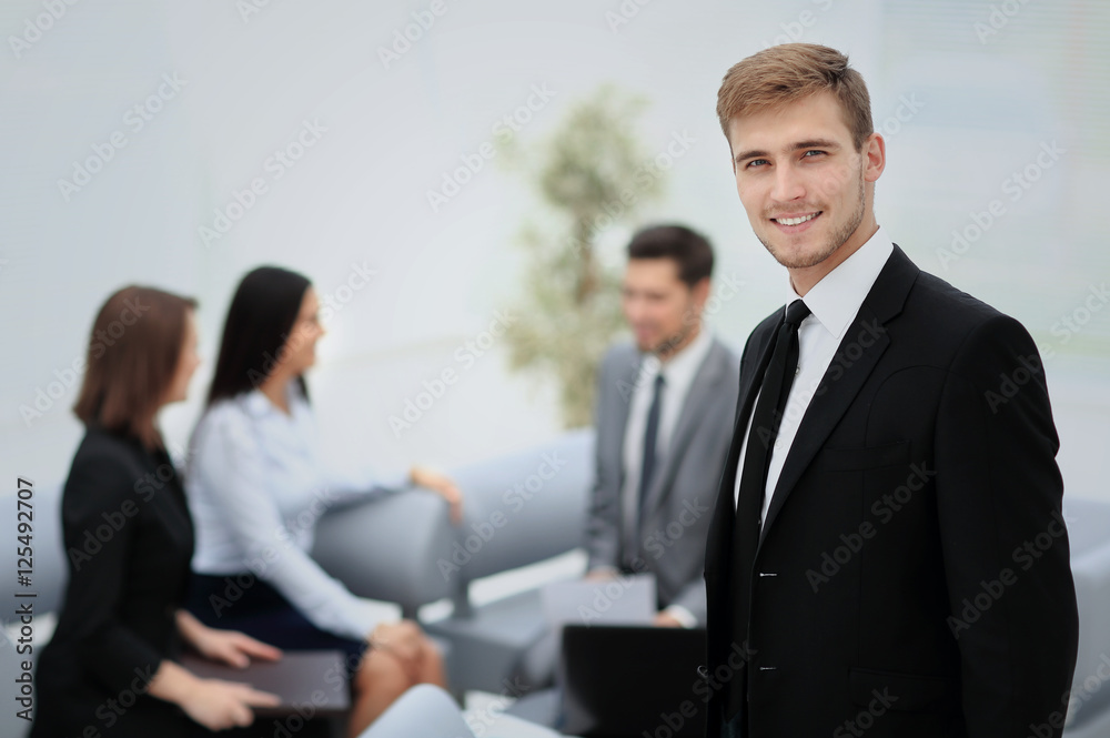 Successful business man standing with his staff in background at Successful business man standing with his staff in background at