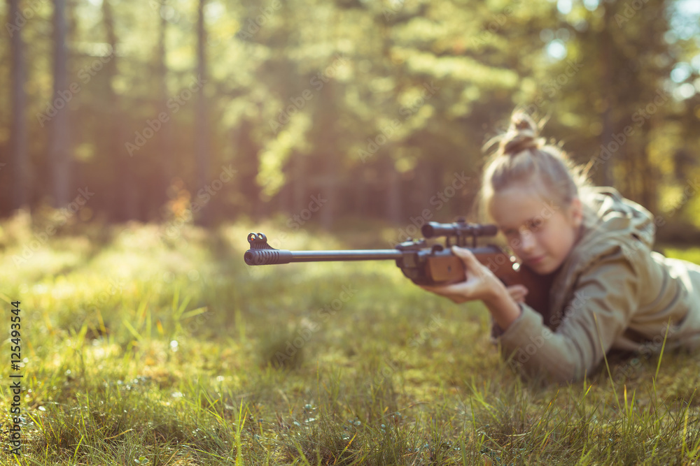 Fototapeta premium Girl shooting from the air rifle in the forest