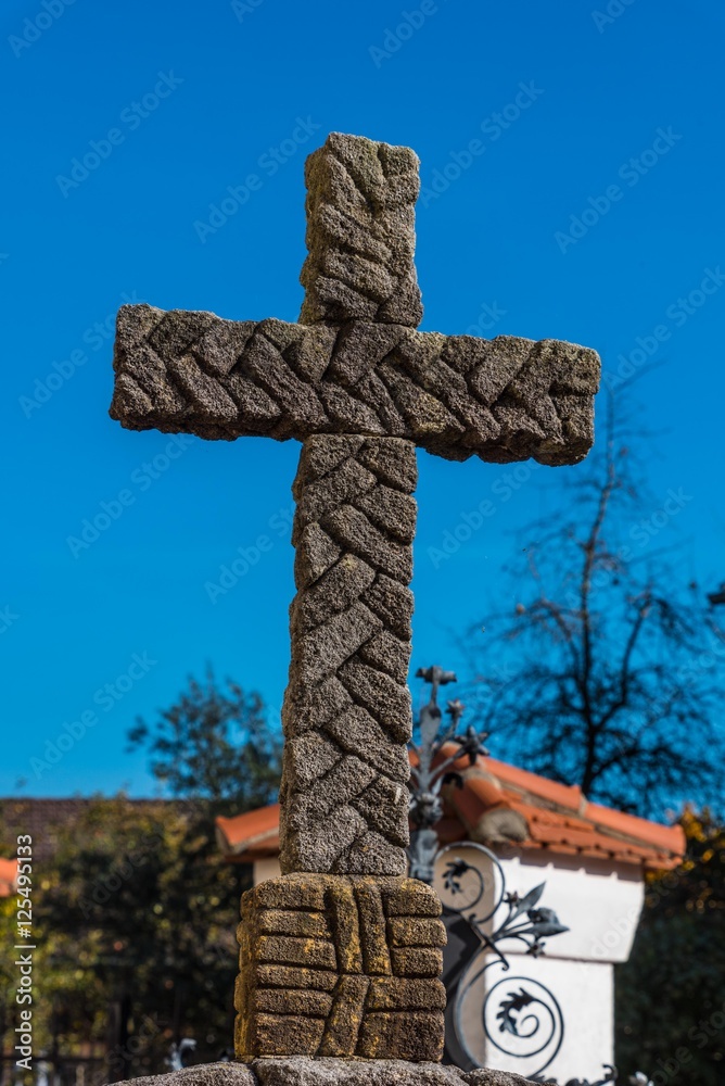 Grabkreuz aus Stein vor blauem Himmel