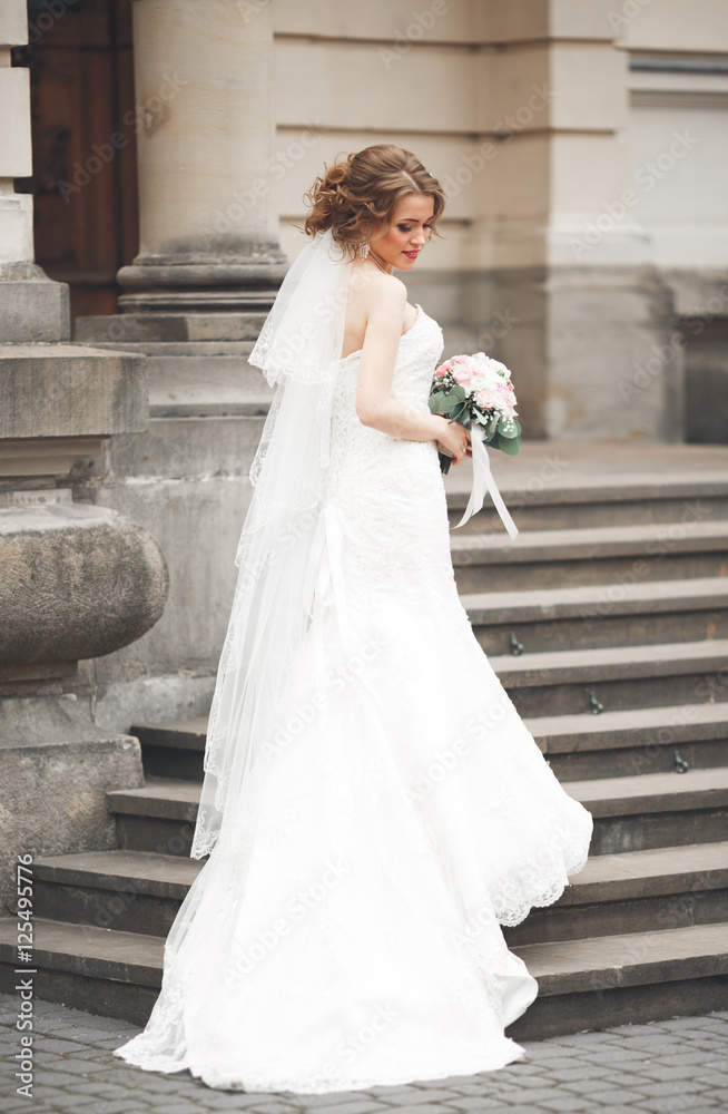 Obraz premium Wonderful bride with a luxurious white dress posing in the old town