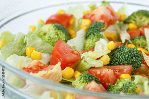 Healthy salad with tomatoes, broccoli, iceberg lettuce and sweet maize corn